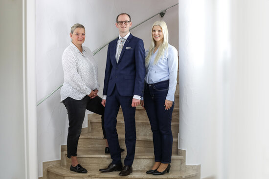 Drei Mitglieder der Geschäftsleitung von der Denkströme auf einer Treppe – professionell, zukunftsorientiert, sympathisch – Businessportrait in heller Umgebung