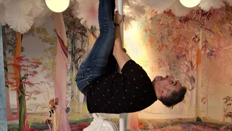 Mitarbeiter hängt lachend kopfüber an Karussell-Stange im fantasievoll gestalteten Traumwald mit rosa Wattebäumen bei Denkströme Event
