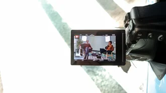 Zwei Personen im Gespräch bei einer Videoproduktion, sichtbar durch das Display einer professionellen Kamera 