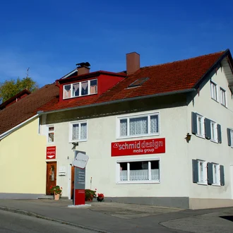 Außenansicht des Agenturgebäudes der schmiddesign media group mit Firmenbeschilderung und Eingangsschild bei sonnigem Wetter – Standortentwicklung und Unternehmenshistorie