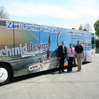 Linienbus mit großflächiger Werbebeklebung der Werbeagentur schmiddesign und Partnerfirma schattmeier – Aufnahme von 2009 mit drei Personen vor dem Bus