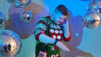 Mitarbeiter in weihnachtlichem Sweater tanzt umgeben von Discokugeln im blau beleuchteten Raum bei Denkströme Event