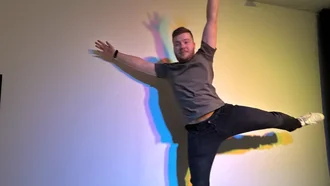 Denkströme Mitarbeiter in Jeans und T-Shirt springt vor bunter Lichtprojektion an der Wand bei Event
