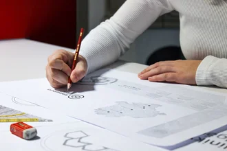 Hand skizziert ein Logo mit rotem Bleistift als Teil eines Markenentwicklungsprozesses.