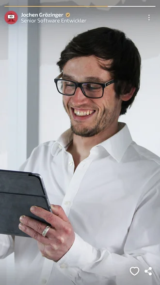 Jochen Grözinger, Senior Software Entwickler bei Denkströme, lächelnd mit Tablet in den Händen, weißes Hemd vor hellem Hintergrund – modernes Mitarbeiterporträt